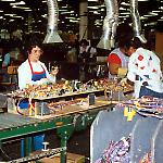 Soldering wire harnesses onto Taxi playfields at the Williams Pinball Factory